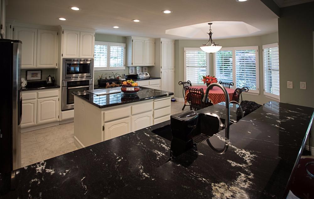 Spacious kitchen with black granite counters, white cabinets, large island and breakfast nook